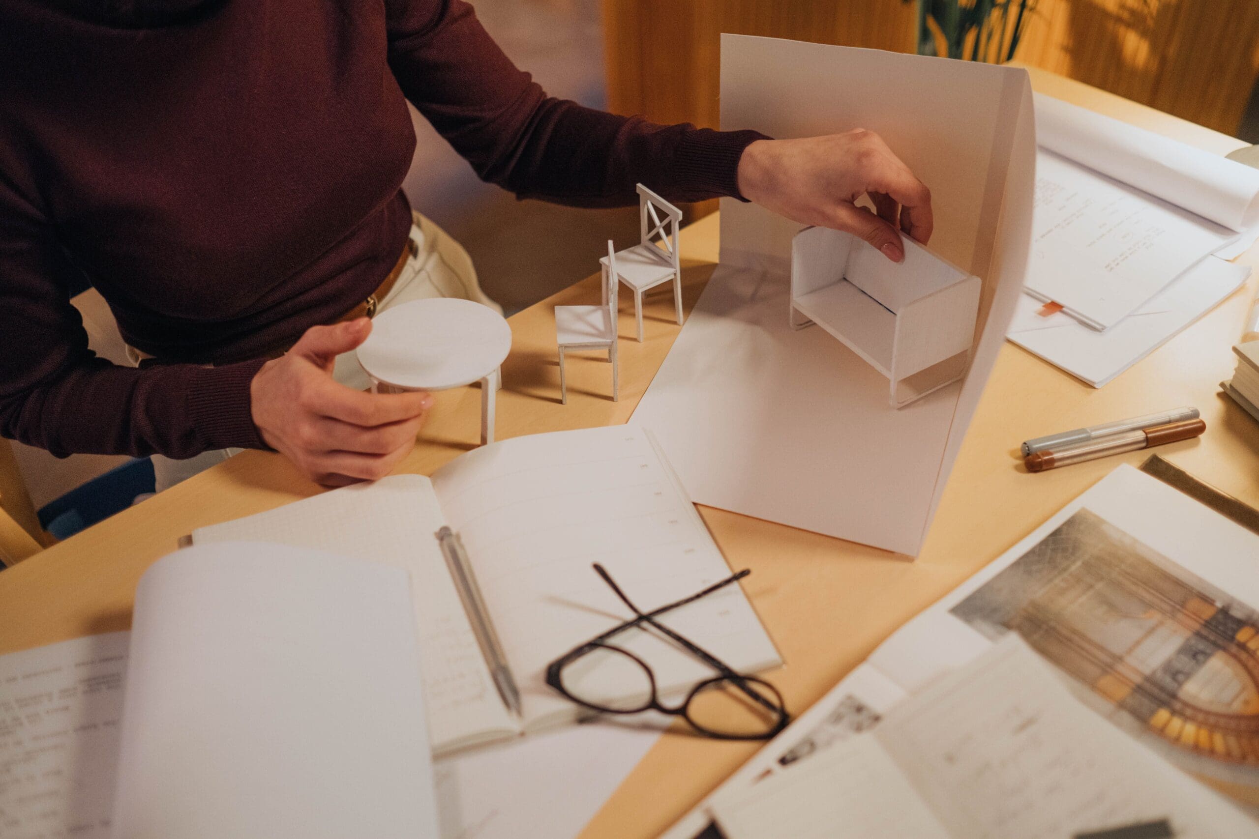 Interior designer creating a furniture layout using a scale model during the planning phase of a residential home renovation.